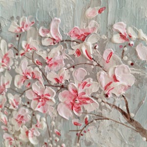 May include: A close-up of a painting depicting a delicate branch of pink and white blossoms. The flowers are painted with thick, textured strokes, giving the painting a three-dimensional effect.