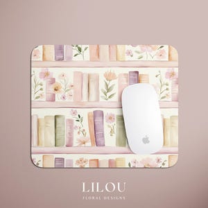 May include: A rectangular mousepad featuring a watercolor design of a bookshelf with books in pastel colors and floral accents. A white wireless mouse rests on the pad. The text "LILOU FLORAL DESIGNS" is at the bottom.
