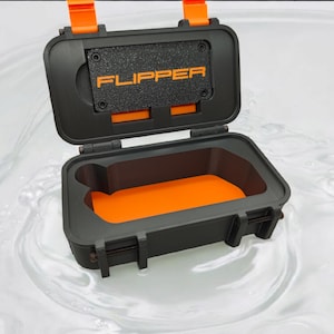 Peut inclure: Une boîte étanche noire avec des accents orange et le mot "FLIPPER" imprimé sur le couvercle. La boîte est ouverte et flotte dans l'eau.