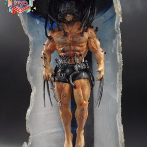 Peut inclure: Figurine détaillée d'une figure musclée avec des griffes métalliques et un casque, placée dans une structure translucide teintée de bleu. La figurine est peinte avec des tons de peau réalistes et porte un short noir. Le logo "ART PLAY LAND" est inclus.