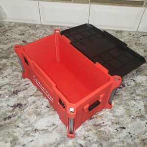 May include: Red plastic storage container with a black lid. The container has the words "Custom Text" printed on the side. The container is open, revealing the interior. The container is sitting on a marble surface.