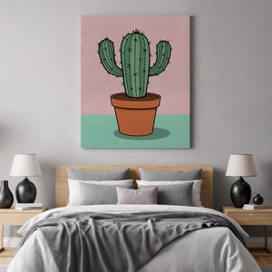 Puede incluir: Impresión en lienzo de un cactus verde en una maceta marrón sobre un fondo rosa y turquesa. El cactus tiene tres brazos y espinas negras. La obra de arte se exhibe sobre una cama con ropa de cama gris y mesitas de noche de madera.