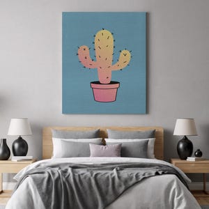 Puede incluir: Impresión en lienzo que presenta un cactus estilizado en una maceta rosa sobre un fondo azul. El cactus es un degradado de amarillo a rosa, con espinas negras. La obra es una ilustración sencilla y moderna.