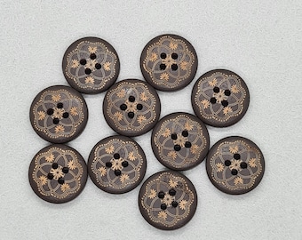 May include: A collection of ten dark brown wooden buttons with a floral design in gold. Each button has four holes and a detailed, symmetrical pattern. The buttons are round and appear to be approximately 1 inch in diameter.