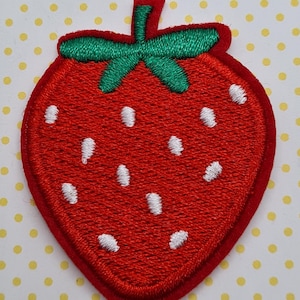 May include: Red felt strawberry patch with white embroidered seeds. The strawberry has a green felt stem and leaves.