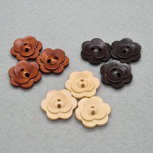 May include: A selection of flower-shaped wooden buttons in shades of brown and cream. The buttons feature a layered petal design and two holes for sewing. Ideal for craft projects, sewing, and adding decorative touches to garments.