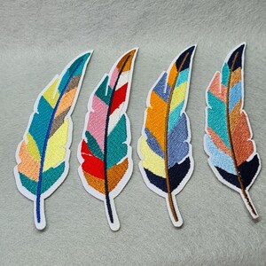 May include: Four colourful embroidered iron-on patches shaped like feathers. The feathers are in shades of blue, green, yellow, orange, pink, and red.
