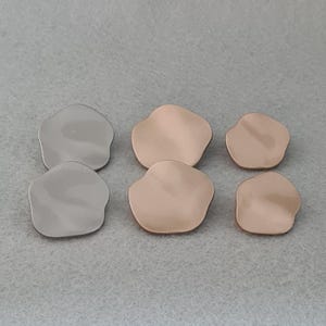 May include: Six metal petal-shaped components in two colours: silver and rose gold. The components have a smooth, slightly reflective surface and a rounded, irregular shape. The components are arranged in a group of six.