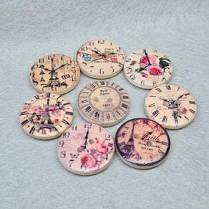 May include: Assortment of eight wooden clock-themed buttons with various designs, including owls, roses, and the Eiffel Tower. The buttons are beige with a cream-coloured background and feature black clock hands and Roman numerals.