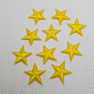 May include: Ten yellow felt star-shaped patches. The stars are approximately 2.5 cm in diameter.