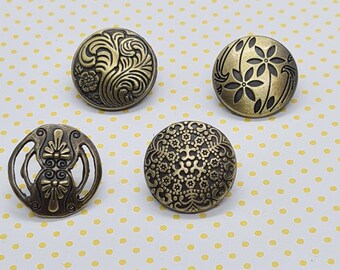 May include: Four decorative metal buttons with intricate floral and geometric designs. The buttons are gold in color and have a slightly raised surface.