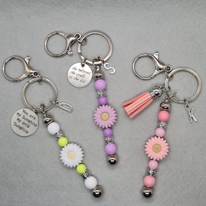GEPERSONALISEERDE DAISY SLEUTELHANGER, tasbedel met kralen en initiaal, quote bedel of beschermengel of kwastje, sleutelhanger tashanger ritstrekker