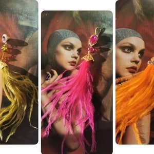 Può includere: Tre paia di orecchini di piume con dettagli dorati e pietre preziose colorate. Gli orecchini sono mostrati su modelli con piume di diversi colori: giallo, rosa e arancione.