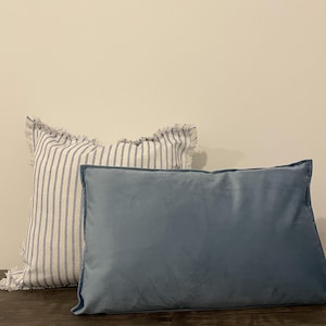 May include: Two decorative throw pillows, one with white and blue stripes and a frayed edge, and the other a solid blue velvet.