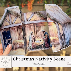 May include: A Christmas Nativity Scene folio set, featuring a watercolor illustration of the holy family in a stable. The scene is set inside a fold-out paper structure with a thatched roof and wooden walls. The text "Christmas Nativity Scene" is visible.