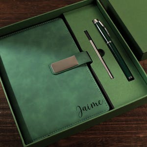 Puede incluir: Un juego de regalo verde que incluye un diario de cuero verde con cierre plateado, un bolígrafo verde y un bolígrafo plateado. El diario lleva el nombre "Jaime". Ideal para escribir y tomar notas.