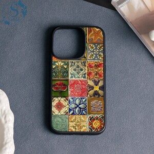 May include: Black phone case with a mosaic tile design. The case has a black border and a square pattern of floral and geometric tiles in red, blue, green, and yellow. The case is designed for a smartphone.