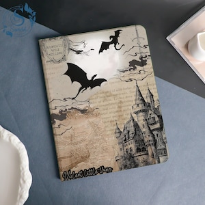 May include: A notebook with a fantasy theme. The cover features a castle, dragons, and a map design. The text includes "Bascilath War College" and "Valent little thing". The color scheme is primarily beige, black, and white.