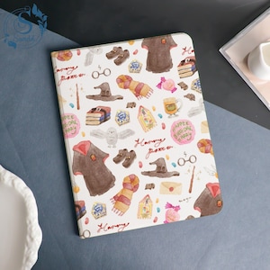 May include: A white notebook with a colorful pattern of Harry Potter-themed illustrations. The design includes images of a wizard's hat, scarf, shoes, and the text "Harry Potter". The notebook is open, displaying the patterned cover.