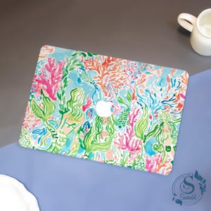 Op de afbeelding: Een laptophoes met een levendig aquarelontwerp met koraal, zeewier en zeemeerminnen in roze, groene en blauwe tinten. De hoes heeft een wit Apple-logo in het midden.