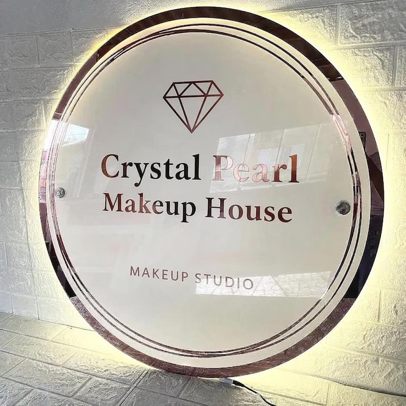 Pu&ograve; includere: Un'insegna rotonda e illuminata con la scritta "Crystal Pearl Makeup House" in oro rosa. L'insegna presenta anche un grafico a diamante e le parole "Makeup Studio". L'insegna &egrave; circondata da un bordo in oro rosa.