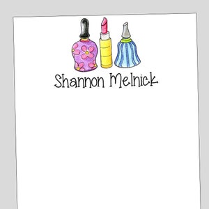 May include: A personalized stationery set with a pink floral perfume bottle, a yellow lipstick, and a blue and white striped bottle. The name "Shannon Melnick" is written in black cursive.