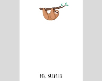 May include: A white card with a brown sloth hanging upside down from a branch with green leaves. The text "MS. SUDMAN" is printed at the bottom of the card.