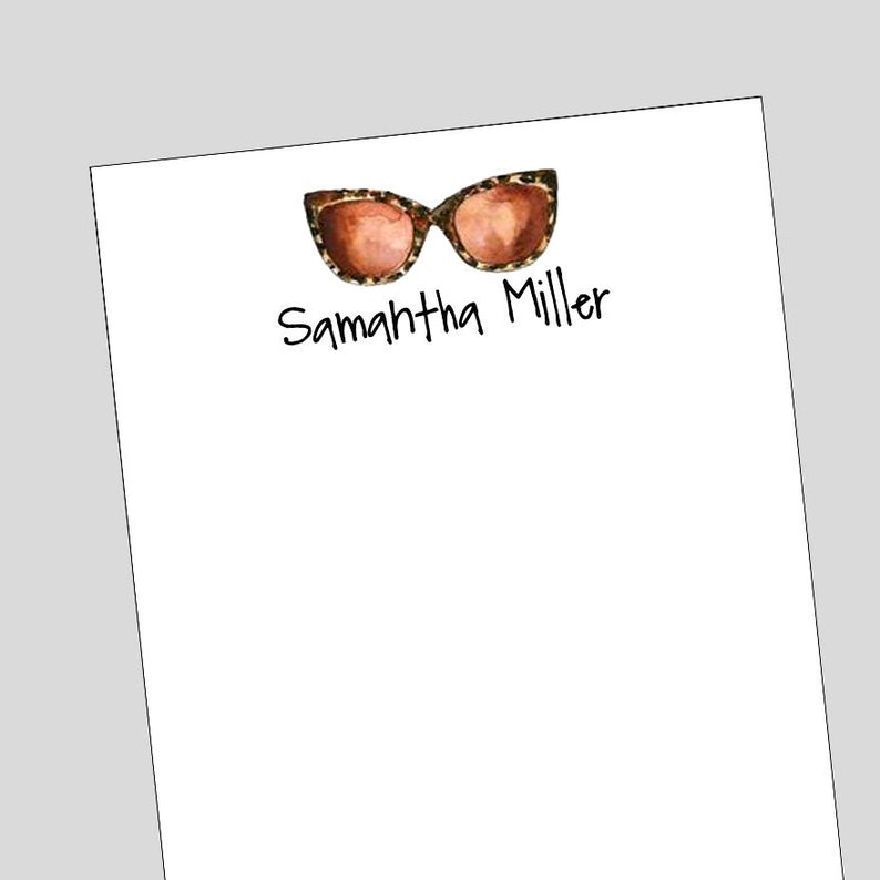 Peut inclure: Un bloc-notes blanc avec un graphique de lunettes de soleil &agrave; imprim&eacute; l&eacute;opard noir et brun et le texte "Samantha Miller" &eacute;crit en noir.