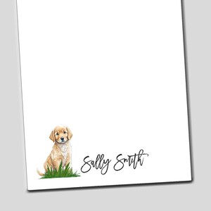 May include: A white notepad with a golden retriever puppy sitting on green grass at the bottom. The name "Sally Smith" is written in cursive at the bottom of the notepad.