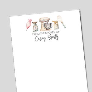 May include: A white stationery sheet with watercolor illustrations of baking tools, including a mixer, scale, and whisk. The text "FROM THE KITCHEN OF Casey Spettz" is printed in a script font.