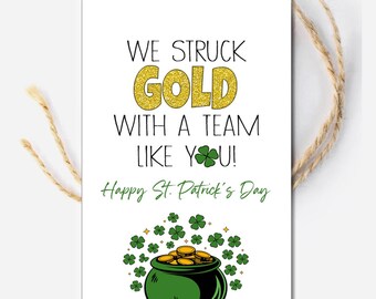 May include: A white card with a green shamrock and gold pot of coins. The text reads "We struck gold with a team like you! Happy St. Patrick's Day."