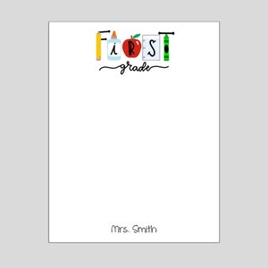 May include: A white notepad with the words "First Grade" written in black cursive. The word "First" is spelled out with school supplies, including a pencil, glue, apple, notebook, and crayon. The teacher's name, "Mrs. Smith", is written at the bottom of the notepad.