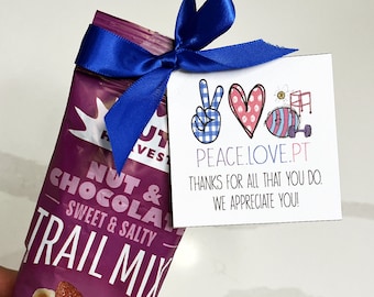 May include: A purple Nut Harvest trail mix snack bag tied with a blue ribbon and a white tag. The tag has the text "PEACE.LOVE.PT" and "THANKS FOR ALL THAT YOU DO. WE APPRECIATE YOU!" with peace sign, heart, and exercise equipment graphics.