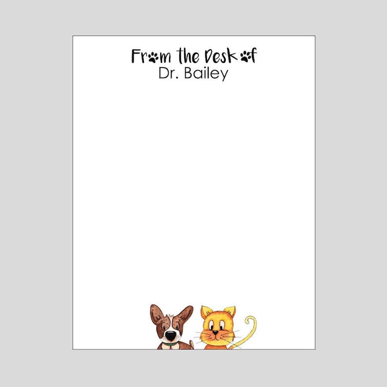 Op de afbeelding: Wit notitieblok met de tekst "From the Desk of Dr. Bailey" bovenaan. Een bruine en witte hond en een oranje kat bevinden zich onderaan het notitieblok.