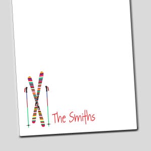 May include: A white notepad with a colorful illustration of crossed skis and ski poles. The text "The Smiths" is written in red at the bottom of the notepad.
