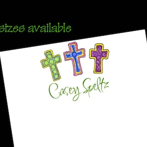 May include: Three colorful crosses with a green, blue, and purple design. The text "Casey Speltz" is written below the crosses.  3 sizes available.