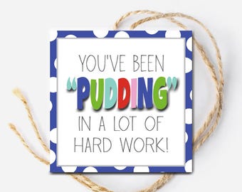 Op de afbeelding: Een blauw en wit gestippeld cadeau-etiket met de tekst "You've been "PUDDING" in a lot of hard work!"