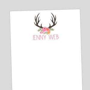 May include: A white notepad with a floral design and antlers. The name "JENNY WEB" is printed in pink below the design.