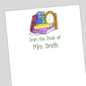 May include: A white card with a colorful illustration of a stack of books, a clock, and glasses. The text "From the Desk of Mrs. Smith" is printed in green.