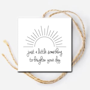 May include: A white card with a black line drawing of a sun with rays. The text "just a little something to brighten your day" is written below the sun.