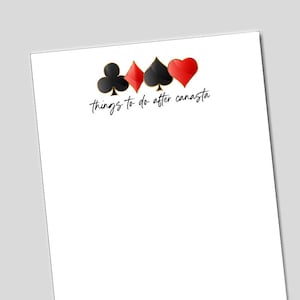 May include: White paper with playing card suit symbols in black, red, and gold. The text "things to do after canasta" is written in a cursive font below the symbols.