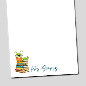 May include: White notepad with a cartoon green caterpillar wearing glasses sitting on a stack of colorful books. The notepad has the text "Mrs. Simpsy" in teal script.