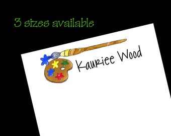 May include: A paintbrush and palette with colorful paint on a white background. The text "Kauriee Wood" is written in black ink.