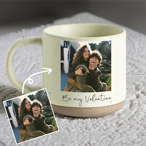 May include: A light green speckled ceramic mug with a brown base. The mug displays a photograph of a couple and the text "Be my Valentine". A smaller version of the photograph is also shown.