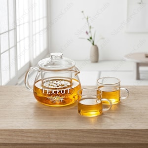 May include: A clear glass teapot with a removable infuser and two matching glass cups, all filled with amber-coloured tea. The teapot features the white printed text "Hudson's TEAPOT" above a small botanical illustration of leaves and berries.