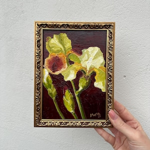 Può includere: Dipinto a olio incorniciato di iris. I fiori sono dipinti in tonalità di giallo, bianco e rosso su uno sfondo bordeaux scuro. La cornice dorata ornata aggiunge un tocco classico all'opera d'arte. Firmato "Maria 20".