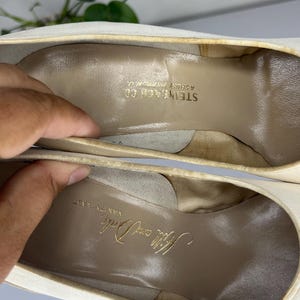 May include: Close-up of the inside of a pair of off-white high heels. The insoles are tan with gold lettering that reads "Hilly and Dale" and "Steinbach Co Asbury Park N.J."