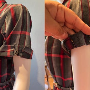 Peut inclure: Une robe &agrave; carreaux grise, rouge et noire avec des manches courtes. Les manches sont retrouss&eacute;es et boutonn&eacute;es. La robe est sur un mannequin.
