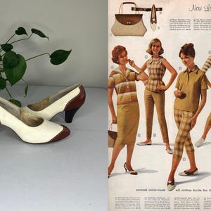 May include: A pair of vintage women's pumps with a two-tone design. The shoes feature a cream-colored body with brown accents on the heel and toe. The heels are approximately 3 inches high. The image also includes a vintage fashion advertisement.
