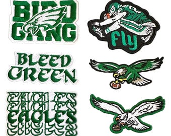 May include: A collection of six embroidered patches featuring Philadelphia Eagles themes. Designs include the text BIRD GANG, a football player with the word FLY, the text BLEED GREEN, the word EAGLES repeated, and two eagle logos holding footballs.